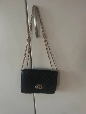 Svart quiltad axelväska med guldkedja -  Säljer en supersnygg väska skriv för fler bilder den är från Gekås och man kan ha axelbandet både långt eller kort man kan reglera det