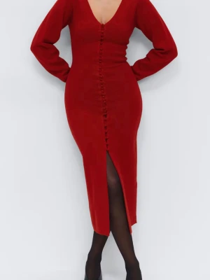 Röd lång stickad klänning Gina Tricot - Röd lång stickad klänning från Gina Tricot med v-ringning, långa ärmar och dekorativa knappar framtill. Klänningen har en slits framtill och figurnära passform som framhäver siluetten. Perfekt för dig som vill ha en trendig och bekväm look.