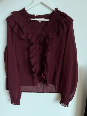 Vinröd volangblus  - Snygg vinröd blus från ONLY med volangdetaljer längs ringningen och framtill. Storlek L🙏men passar mig som är M