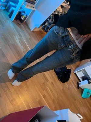 Blå bootcut jeans - Säljer ett par klassiska blå bootcut jeans med låg midja och snygga detaljer vid fickorna. Jeansen har en avslappnad passform och är tillverkade i slitstarkt denimtyg. Perfekta för en casual och trendig look.