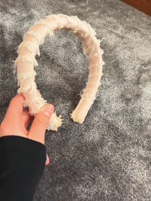 Ljusrosa diadem med fransar - Säljer ett fluffigt ljusrosa diadem med tyg i lager och fransiga detaljer som ger en trendig och avslappnad look. Diademet är vadderat för extra komfort och har en bred form som syns snyggt i håret. Perfekt accessoar för att lyfta din outfit. Tyvärr rejäla smink fläckar men inget som syns men priset är betydligt lägre. 