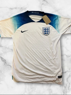 England fotbollströja - Hej! Säljer en England-fotboll t-shirt som är oanvänd eftersom beställde fel storlek. En jätte fint och lysande fotboll tröja. Passar med allt. 