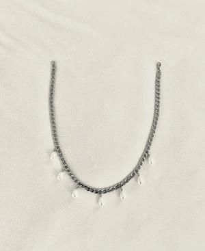 Silverfärgat halsband med pärlor - Snyggt halsband i silverfärgad metallkedja med små vita pärlor som hänger längs kedjan. Perfekt accessoar för att lyfta din outfit med en trendig touch. Enkel design som ändå sticker ut med sina pärldetaljer.