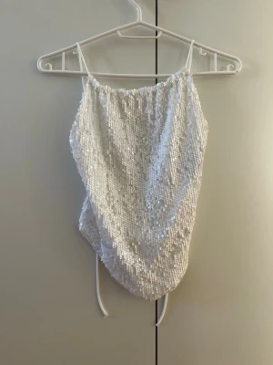 Vit paljettlinnetopp med knytband - Vit glittrig topp från Gina Tricot med öppen rygg. 