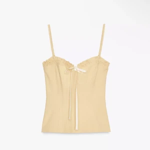 Beige linnetopp med smala axelband - Snygg beige linnetopp med smala axelband och söt knytning framtill. Toppen har rynkade detaljer vid bysten och en figurnära passform som ger en feminin siluett. Perfekt att styla med jeans eller kjol för en trendig look.