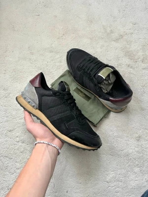 Valentino Rockrunner Skor - Valentino Rockrunners i en riktigt clean modell! Bra skick, finns en liten defekt vid snörningen. Dustbag ingår. Uk 8, storlek 41,5-42. Kontakta mig för fler frågor och funderingar!