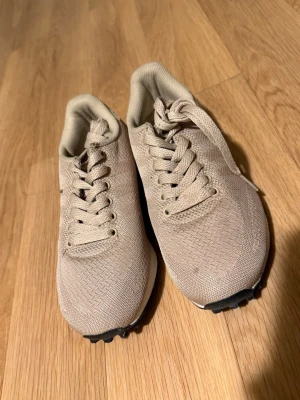 Adidas sneakers - Snygga beige sneakers från Adidas med klassisk låg profil och ovandel i meshmaterial. Skorna har vita detaljer och snörning framtill. Adidas-logga syns på insidan.