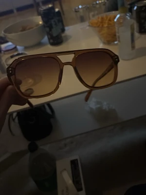 Bruna pilotbågar solglasögon retro - Snygga solglasögon med pilotbågar i transparent brun plast och bruna tonade glas. Klassisk retrostil med dubbla bryggor och markerade detaljer vid gångjärnen. Perfekta för dig som vill sticka ut med en vintagevibe.