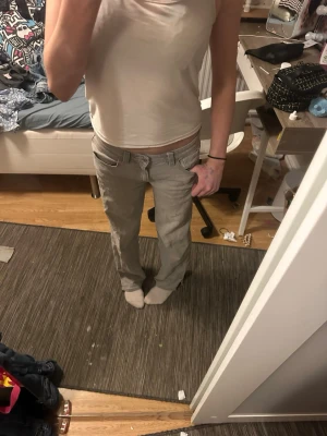 Grå raka jeans med fickor - Säljer ett par grå jeans med raka ben och stora fickor fram. Jeansen har låg midja och bälteshällor. Perfekta för en avslappnad och trendig look. Materialet känns som bomull med lite stretch.