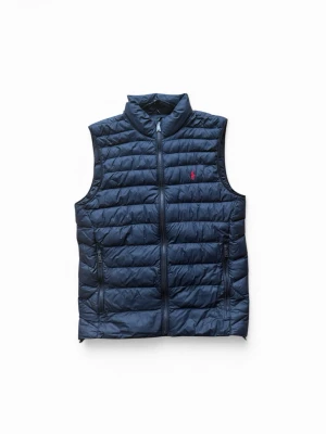 Mörkblå dunväst från Polo Ralph Lauren - Snygg mörkblå dunväst från Polo Ralph Lauren med quiltad design, hög krage och dragkedja framtill. Västen har två praktiska fickor med dragkedja och en liten röd logga på bröstet. Perfekt för lager på lager och streetstyle.