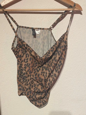 y2k Leopardmönstrat linne - Snyggt linne från H&M med leopardmönster i bruna och svarta toner. Tunt, lätt material med justerbara smala axelband och djup urringning. Perfekt för dig som vill sticka ut med ett trendigt djurmönster.