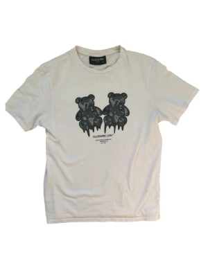 Essentials closure vit t-shirt - Vit t-shirt från Essentials med svart tryck av två björnar på bröstet. Klassisk rund hals och korta ärmar. Tillverkad i mjuk bomull för en skön känsla. Perfekt för en avslappnad och trendig stil.