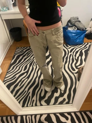 Beiga low waist jeans bootcut - Säljer ett par beiga low waist jeans med bootcut passform. Jeansen har klassiska fem fickor och stängs med knapp och dragkedja. Perfekta för dig som gillar en avslappnad och trendig look. Materialet känns mjukt och följsamt. 