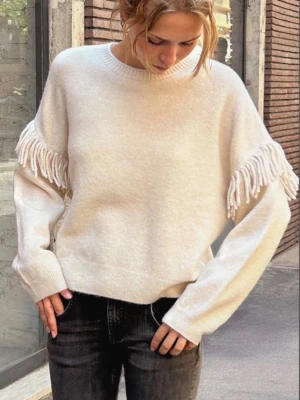 Beige stickad tröja med fransar - Trendig beige stickad tröja med fransdetaljer längs ärmarna. Använd två gånger kostar ca 700 nypris går ner i pris vid snabb affär 