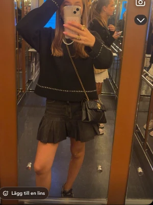 Svart volang jeanskjol - Snygg svart kort jeanskjol med volanger och rå kant. Klassisk femficksmodell med knapp och dragkedja framtill. Perfekt för att skapa en cool och trendig look.