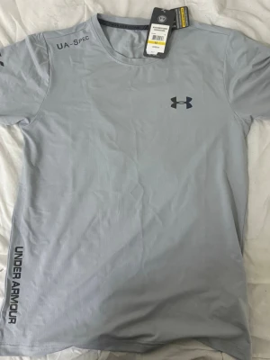 Ljusgrå träningströja Under Armour -  Säljer ett par helt nya  Under Armour , aldrig använda.