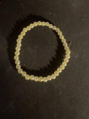 Elastiskt pärlarmband i pärlemor - Snyggt armband med små, runda pärlor i pärlemor-look. Armbandet är elastiskt och passar de flesta handleder. Perfekt för dig som gillar en klassisk och stilren accessoar med en touch av vintagekänsla.OBS! Materialet är okänt, kan ej garantera att det är rostfritt.