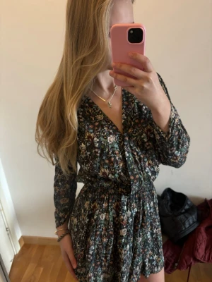 Blommig kortklänning Zadig & Voltaire - Supersnygg kortklänning från Zadig & Voltaire med blommigt mönster i flera färger. Klänningen har v-ringning, lång ärm och markerad midja med resår. Perfekt för dig som gillar en feminin och trendig stil.