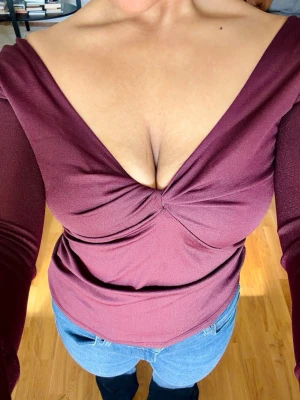 Vinröd v-ringad topp med twist - Snygg vinröd långärmad topp med djup v-ringning och twistad detalj framtill. Figurnära passform och stretchigt material som ger en smickrande siluett. Perfekt att styla med jeans eller kjol för en trendig look. Använd en gång. 