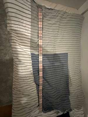 Beige Burberry bälte med TB-spänne - Säljer ett beige bälte från Burberry med klassiskt rutmönster i rosa och grått. Bältet har ett stilrent metallspänne med TB-logga i silverfärg. Perfekt accessoar för att lyfta din outfit med en lyxig touch.