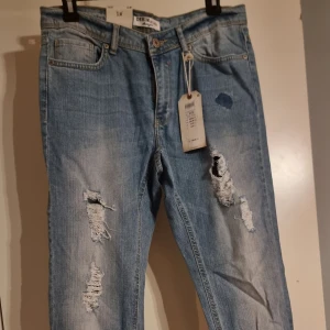 Ljusblå slitna jeans från Denim by lindex - prislapp kvar! - Säljer ett par ljusblå jeans från Denim by lindex med trendiga slitningar och hål på både lår och knä. Klassisk femficksmodell med normal midja och raka ben. Perfekta för en avslappnad streetstyle-look. Helt nya med prislapp kvar!
