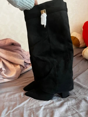 Svarta stövletter från Truffle Collection - Snygga svarta stövletter i mockaimitation från Truffle Collection. De har spetsig tå, bred klack och går upp till knäet. Perfekta för att lyfta vilken outfit som helst med sin stilrena look och trendiga form. 36, 3