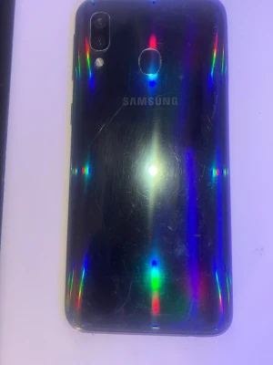 Samsung Galaxy svart Android-telefon - Snygg svart Samsung Galaxy Android-telefon med rundade hörn och fingeravtrycksläsare på baksidan. Telefonen har dubbla kameror och LED-blixt. Baksidan är i plast med en glansig finish som reflekterar ljus i regnbågsfärger.