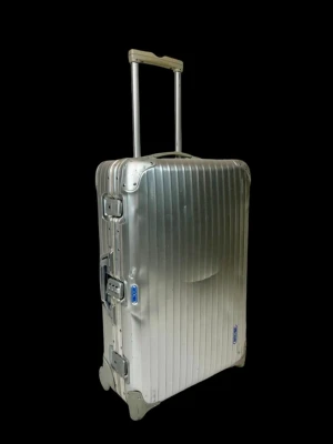 Rimowa resväska  - Stilren och robust resväska i aluminium från Rimowa. Väskan är i aluminium med räfflad yta, teleskophandtag och 2 silikonhjul för enkel transport. Dessa går att rulla på gatsten eller ojämnt underlag vilket fungerar betydligt sämre med 4 små hjul. Ikonisk design med metallhörn och två lås på sidan. Perfekt för dig som vill resa med stil. Går att göra väldigt personlig företrädesvis med Rimowas egna klistermärken, se vidare på Ebay.com. Väskans mått är höjd 65 cm bredd 44 cm djup 19 cm.