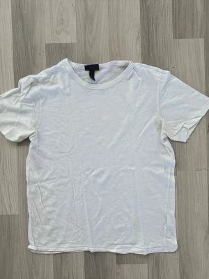 Vit basic t-shirt med rund hals - En enkel vit t-shirt med rund hals och korta ärmar. Perfekt till alla outfits och lätt att matcha. Tillverkad i mjuk bomull för skön känsla hela dagen.