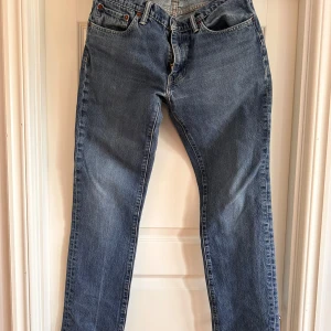 Levi's 511 blå jeansbyxor - Klassiska blå Levi's 511 jeans med fem fickor och raka ben. Byxorna har normal passform och är tillverkade i slitstarkt denim. Perfekta för dig som gillar tidlös stil och vill ha ett par jeans som funkar till det mesta. Jättebra skick.