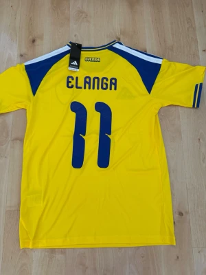 Elanga #11 – Sverige Hemma (storlek M) - Elanga #11-tryck. Sverige Hemma (gul). Storlek M. Helt ny och aldrig använd. Skickas snabbt 🚚💨  Mått (M): Halvt bröstmått 53 cm • Längd 74 cm • Ärmbredd 23 cm • Axelbredd 44 cm • Ärmlängd 40 cm • Manschett 19 cm.  🔥 Fan Edition – normal passform. 🇸🇪 Sverige landslag.  📩 Frågor eller prisförslag? Skicka gärna ett meddelande! 🛍 Bundle-rabatt upp till 20% 💰 📦 Skickas samma eller nästa dag 🌟