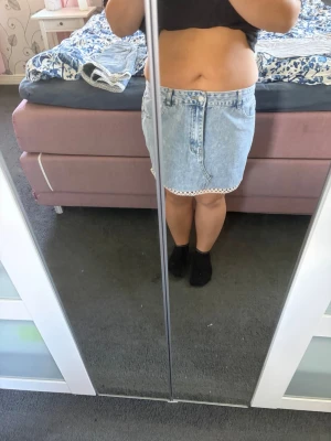 Ljusblå jeanskjol med spetskant - Säljer en ljusblå jeanskjol med snygga fickor fram och dekorativ vit spetskant längst ner. Kjolen har en klassisk denimlook och är kort i modellen, perfekt för dig som gillar en enkel och trendig stil. Jag har sytt den själv först var det ett par jeans 