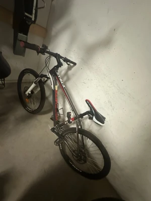 Svart och röd mountainbike X-Trail - Säljer en helt ny svart och röd mountainbike från X-Trail med grova däck, raka styren och vit framgaffel. Cykeln har sportig design, svart sadel med röda och vita detaljer samt tydliga X-Trail-loggor på ramen. Perfekt för dig som gillar att cykla i terräng eller stad.Flera växlar och pris kan diskuteras 