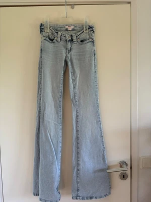 Ljusblå runaway jeans från Gina Tricot 14+ - Säljer ett par ljusblå bootcut jeans från Gina Tricot. Jeansen har klassisk femficksmodell, låg midja och utsvängda ben. Tillverkade i mjuk denim med bälteshällor och knappgylf. Perfekta för en trendig och avslappnad look. Fint skick, inte använda många gånger. Jag är nästan säker på att dem är i tall modellen.