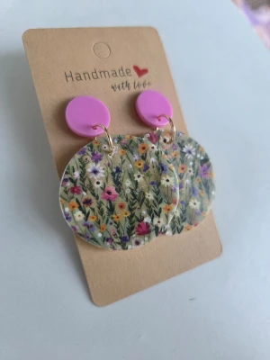 Handgjorda blommiga örhängen - Unika handgjorda örhängen med stora runda hängen i akryl med färgglatt blommönster och rosa knappar upptill. Gjorda för hand av mig i polymerlera. 