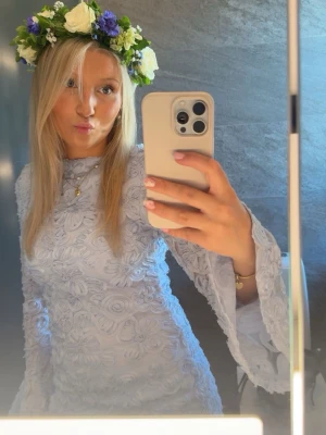 Ljusblå sommarklänning  - Superfin ljusblå kort klänning med blommig spets och utsvängda långärmar. Perfekt för sommarens tillfällen. Använd endast en gång och är inga defekter.
