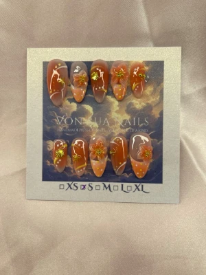 Solaria (S);Mediul Almond - Snygga handgjorda press-on naglar i orange 🍊 och nude ton med handgjorda blommor, vita french med ombre och små guld detaljer. Naglarna har en medium lång almondform och dekoreras med 3D-blommor och prickar för en unik look. Perfekt för dig som vill ha något extra till naglarna!S: 15 mm, 11,5 mm, 12 mm, 11 mm, 9 mm 