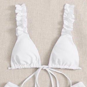 Vit bikiniöverdel med volanger  - JÄTTE FIN bikiniöverdel. helt ny men var tyvärr för liten för mig o jag råkade dra bort lappen😢😢  hur fin som helst!! Passar om man har ca A kanske litem B kupa. Man knyter den i ryggen så passform i ryggen bestämmer man själv!!