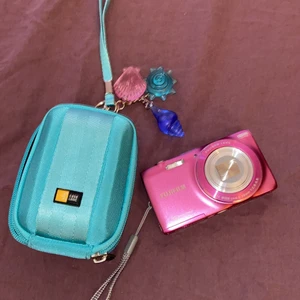 Rosa kamera - En kamera ifrån 2012 som tar snygga ”00’s” bilder. Och går även att filma med. Laddare och fodral skickas med. 