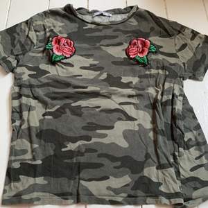 Camouflage mönstrad t-shirt med rosor påsydda. Strl XS. Säljer pga att det tyvärr inte kommer till användning 💞