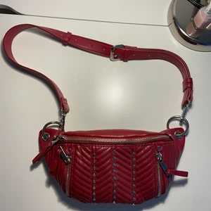 Zara väska röd - Hej, säljer en röd Zara väska med silverdetaljer! Köpt i butik för några år sedan och har sedan dess aldrig kommit till användning. Har ett stort fack med dragkedja och sedan ett fack inuti (se sista bild)❤️ skriv vid intresse