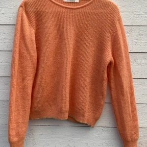 Långärmad stickad tröja i fin aprikos - Jätteskön stickad tröja i aprikos med små, nätta gulddetaljer på vissa sömmar. 