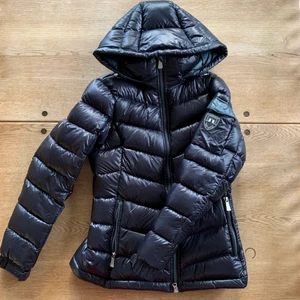 J.Lindeberg Dunjacka  - Äkta dunjacka från J.Lindeberg i stl S. Mörkblå lite glansig utsida. Lite midjeformad, mellantjock och knappt använd. Håller värme bra pga äkta dun. Söker relativt snabb deal därav priset! 