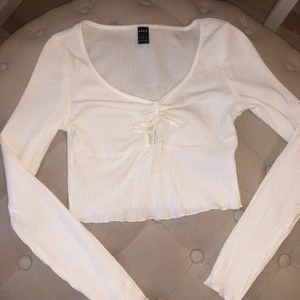 Topp - En fin vit tröja med en liten rosett på framsidan. Tröjan är ganska tunn och lite genomskinlig. Aldrig använt. Frakt betalas av köparen.