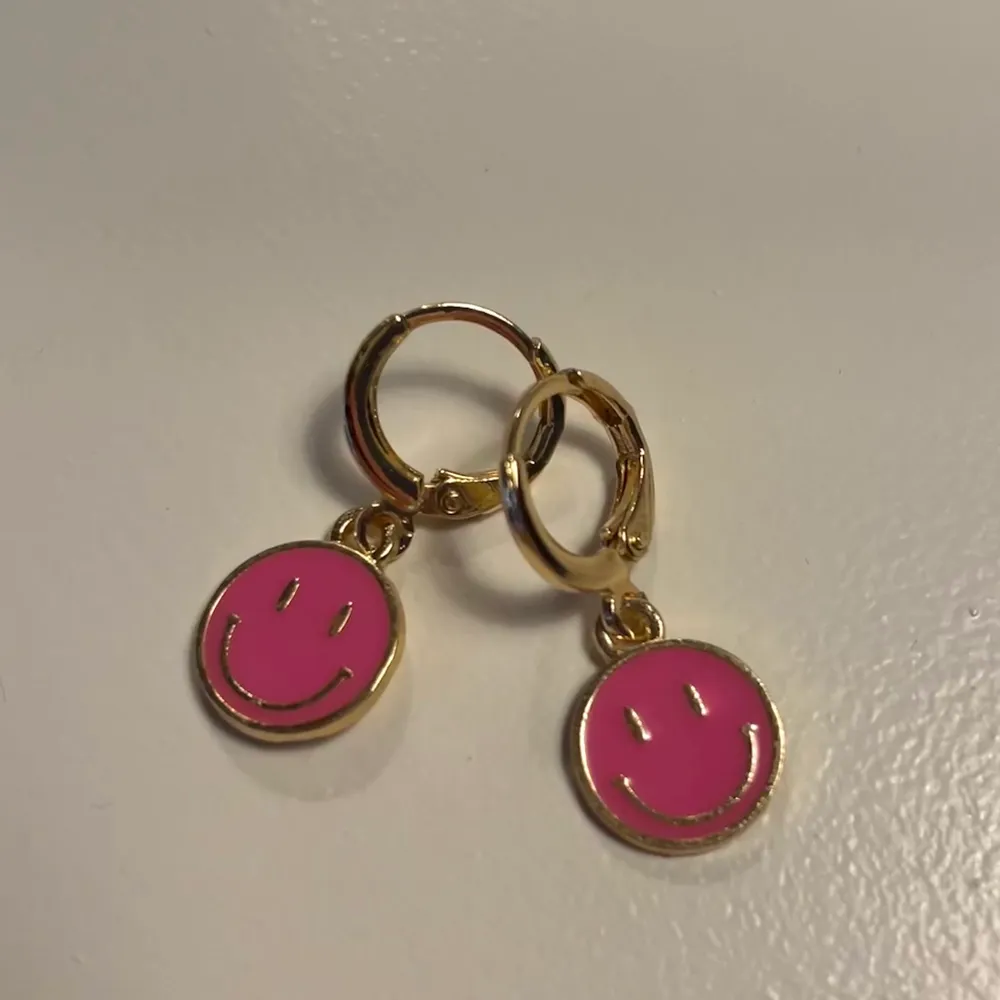 Guldiga örhängen med rosa smiley💕 Har 5 st par av dessa örhängen 🥰 24kr för frakten 🤍. Accessoarer.