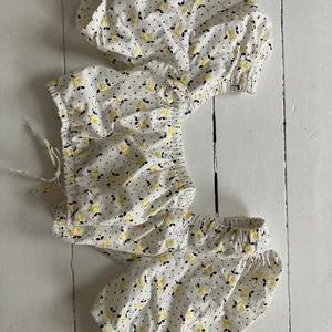 Topp - Söt topp med blommor på ifrån Zara. Endast använd ett fåtal gånger. Den har en fin detalj i ryggen med en knytning. Ganska puffiga armar också.Den slutar undefär lite ovanför naveln så den är ganska kort men skönt till sommar. Storlek Xs