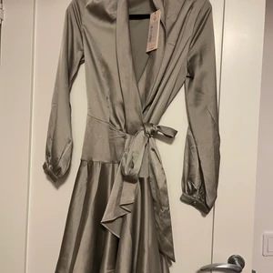 Siden klänning  - En oanvänd siden kläning som knutes runt midjan med tillkommande band. Lappen är fortfarande kvar och klänningen är köpt hos antingen pretty little thing eller missguided.