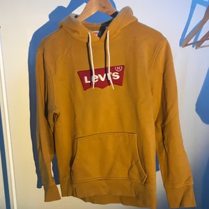 Levis Hoodie - Gul hoodie med röd Levis logga i storlek small. Genomgående ficka, lite oversized.