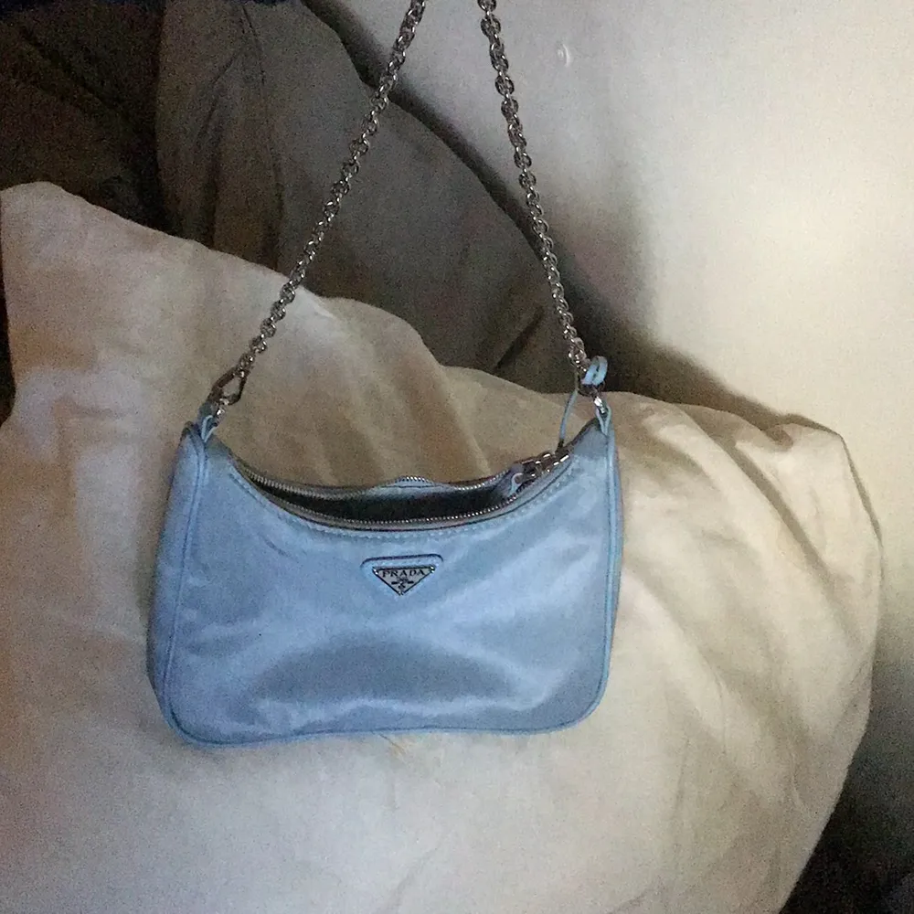 Säljer min fina ljusblå Prada väska (fake). Köpt utomlands och ser ut som äkta. Jättebra skick. Köpt för 500. (Man får med det andra bandet också). Väskor.