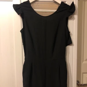Svart byxdress - Säljer en svart byxdress som är oanvänd med lappar kvar. Nypris var 379kr och den är i storlek 36. Det är öppen rygg med knytning som man knyter själv. Även fickor på båda sidor fram. Kan skicka om köparen betalar frakt.